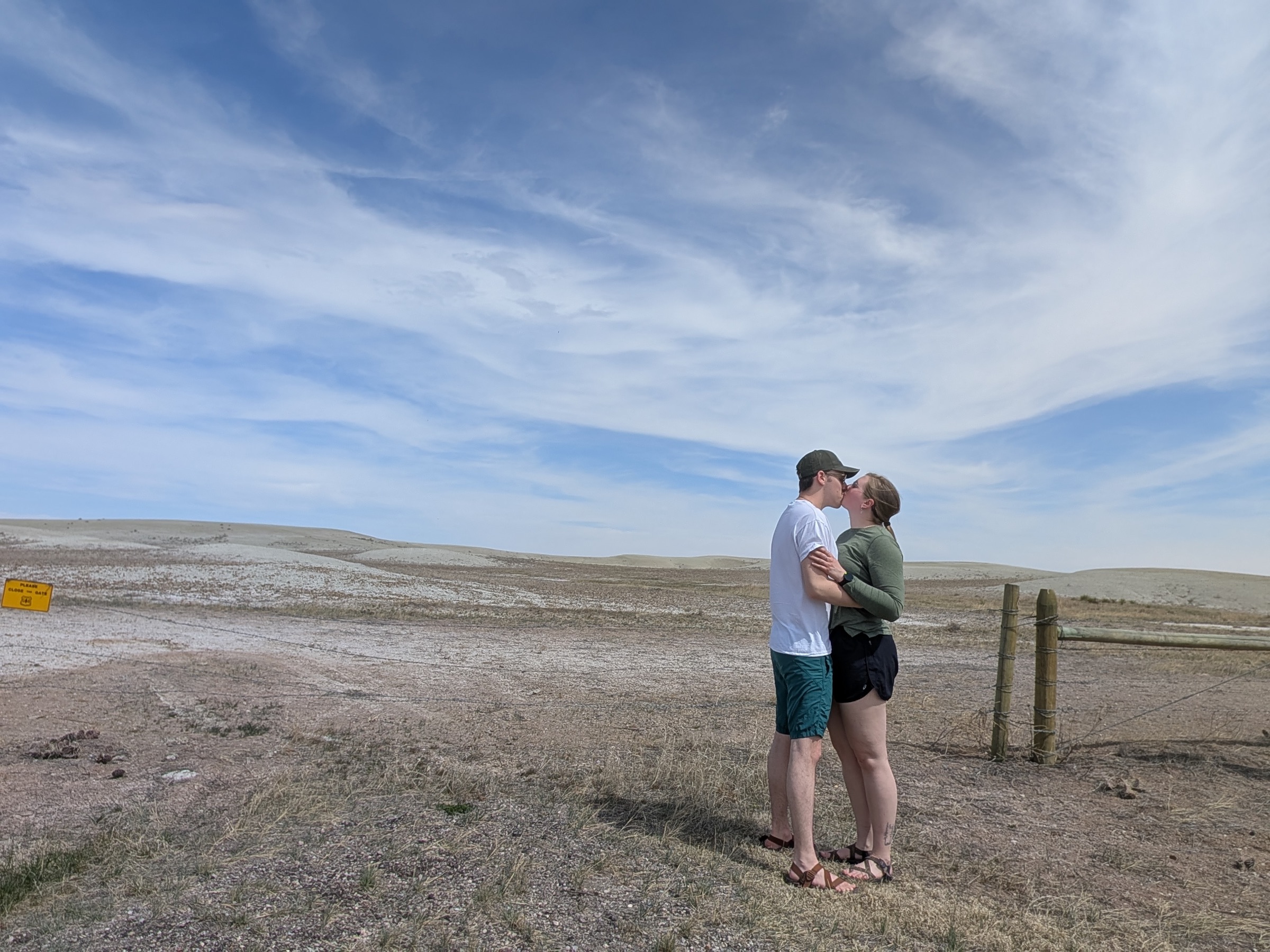 Jenny and Tanner sharing a kiss under a wide prairie sky