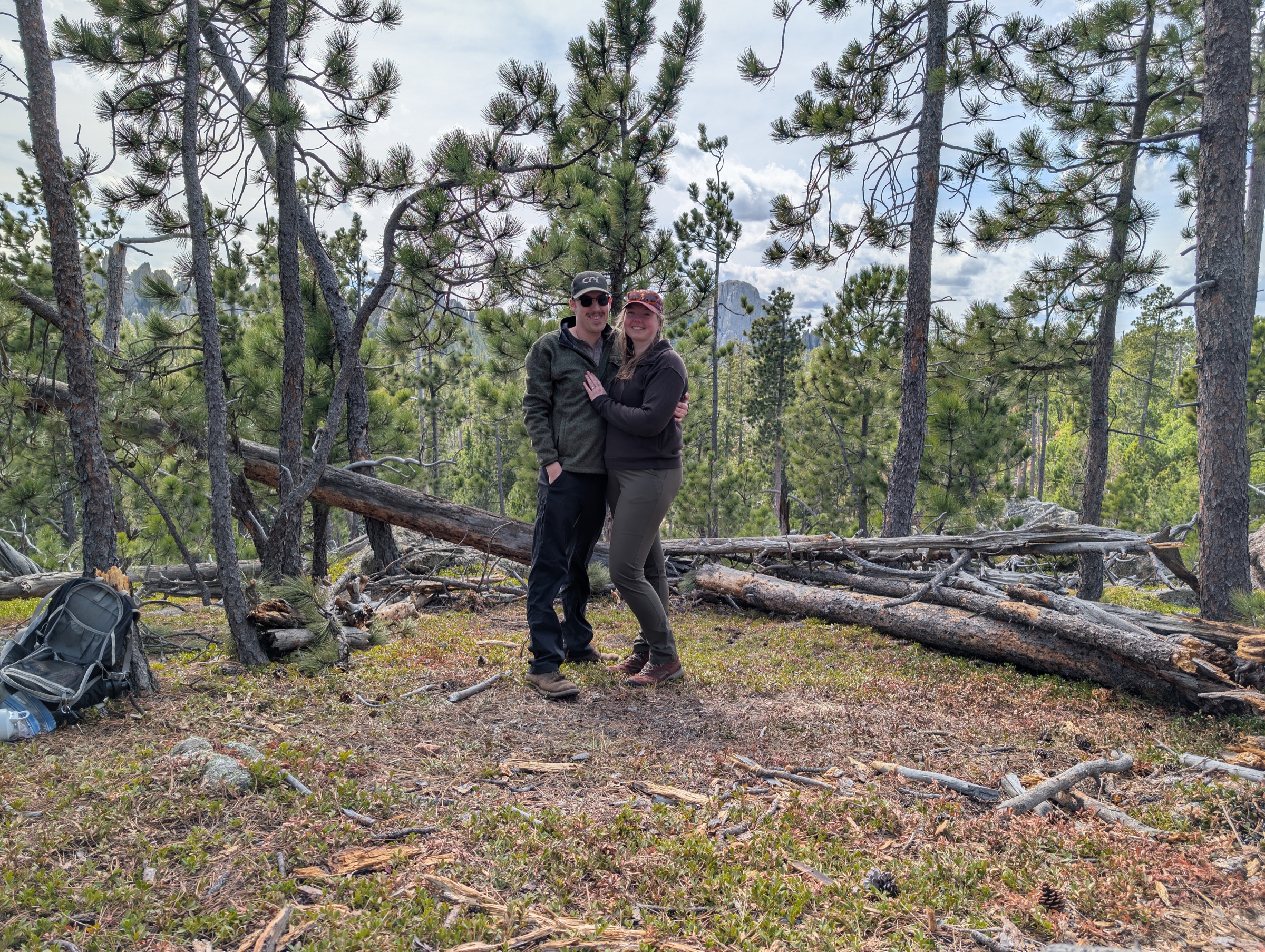 Jenny and Tanner embracing in a forest clearing