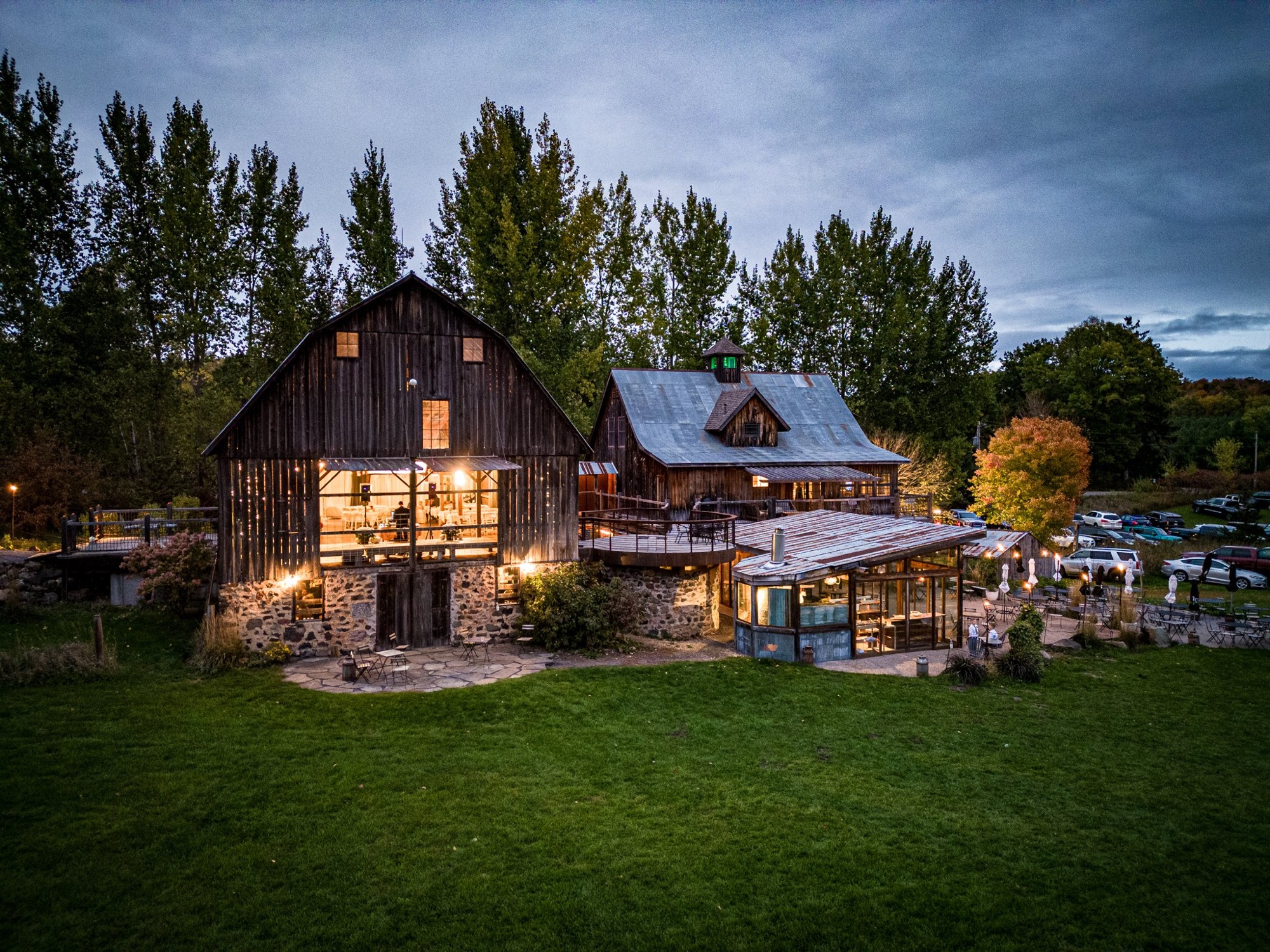 The Enchanted Barn at twilight, with warm lights glowing inside and a wide lawn in the foreground